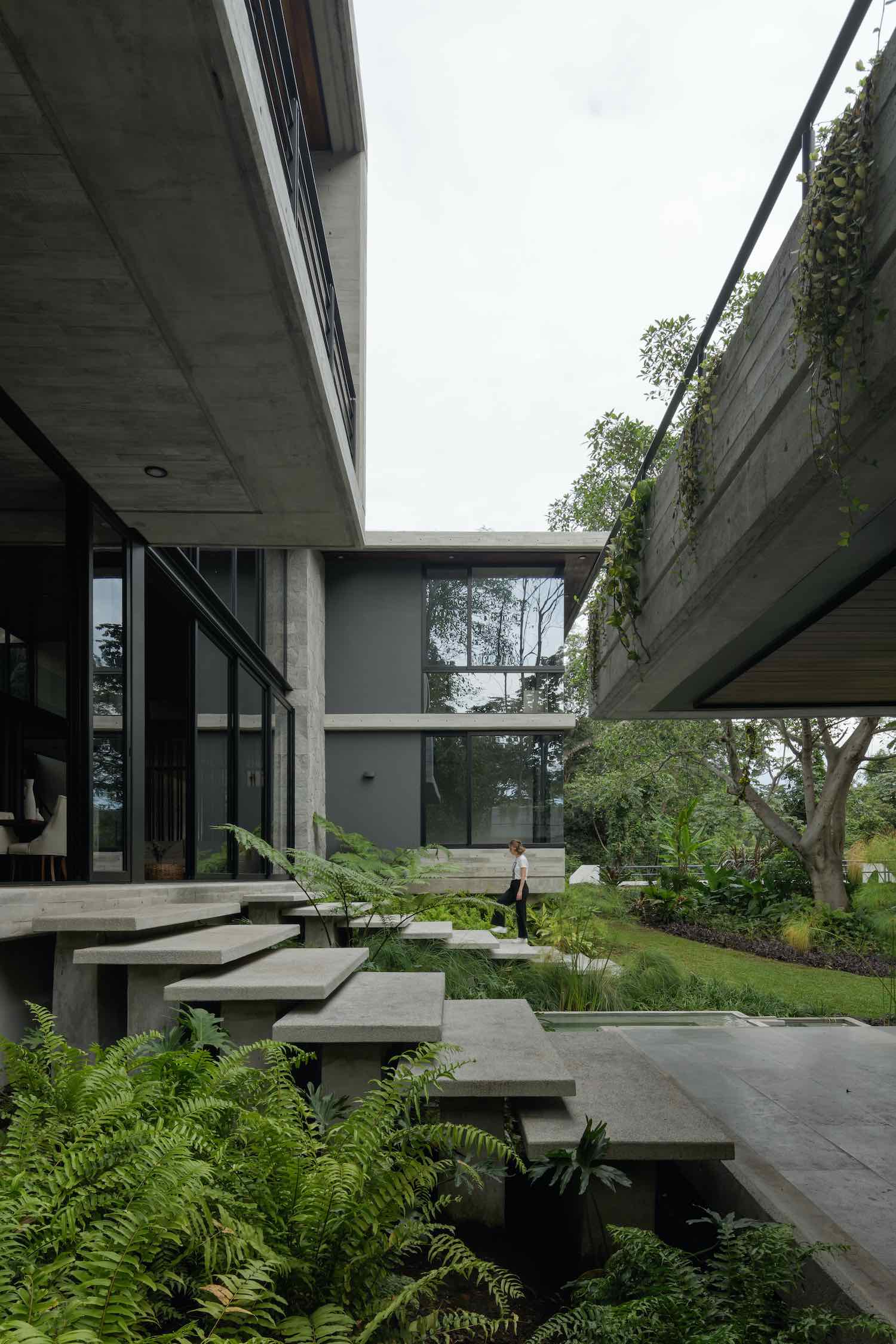 a woman walking on the concrete steps toward the entrance of the house 